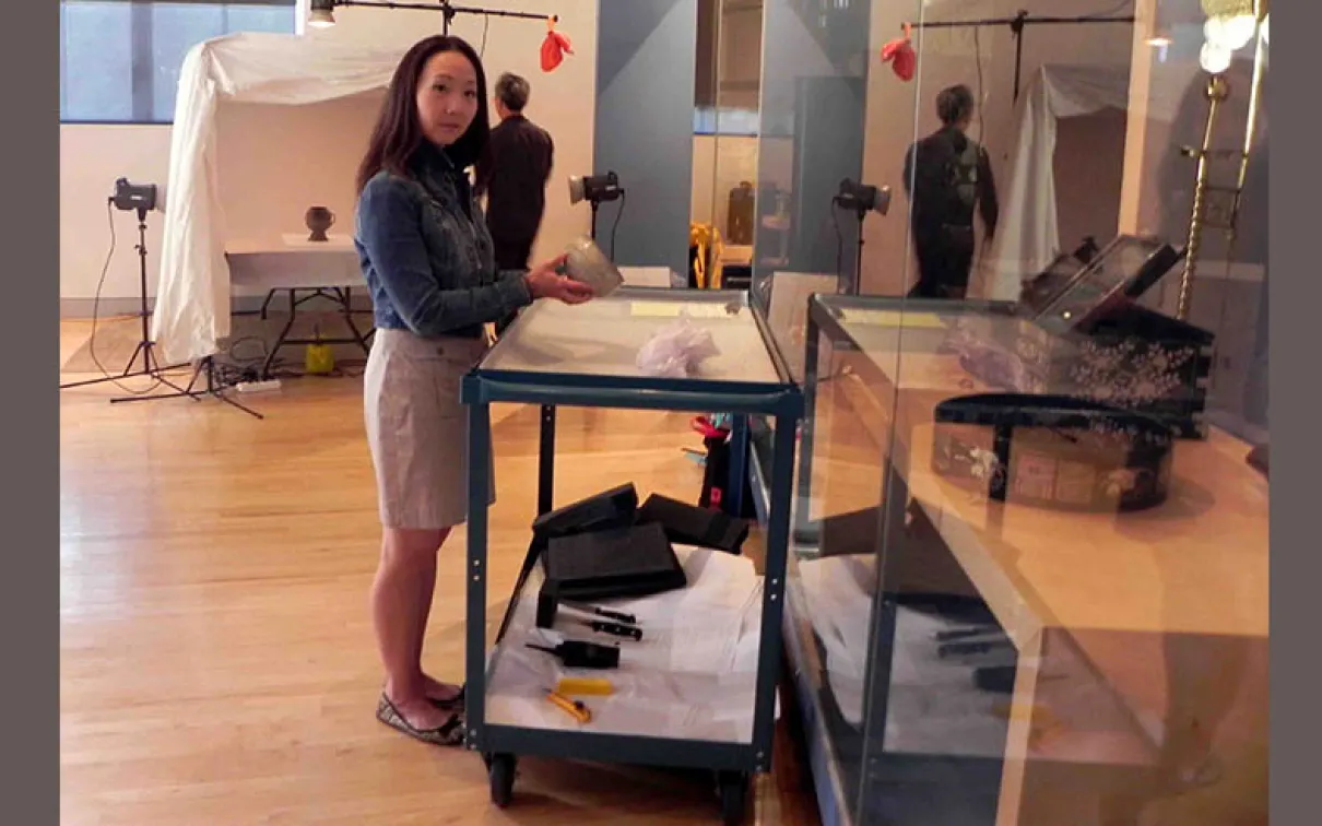 A woman standing next to a desk with a box on it inside a museum gallery space.