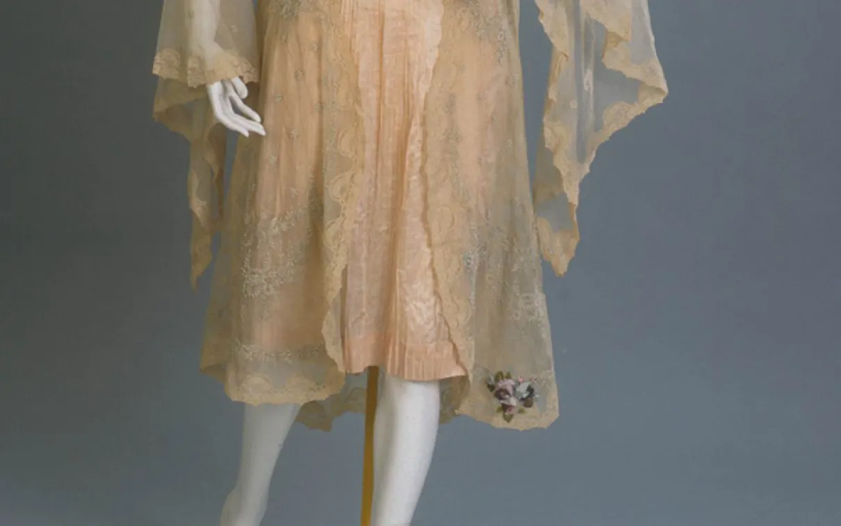 Vintage lace dress with sheer overlay and floral embroidery near the hem.