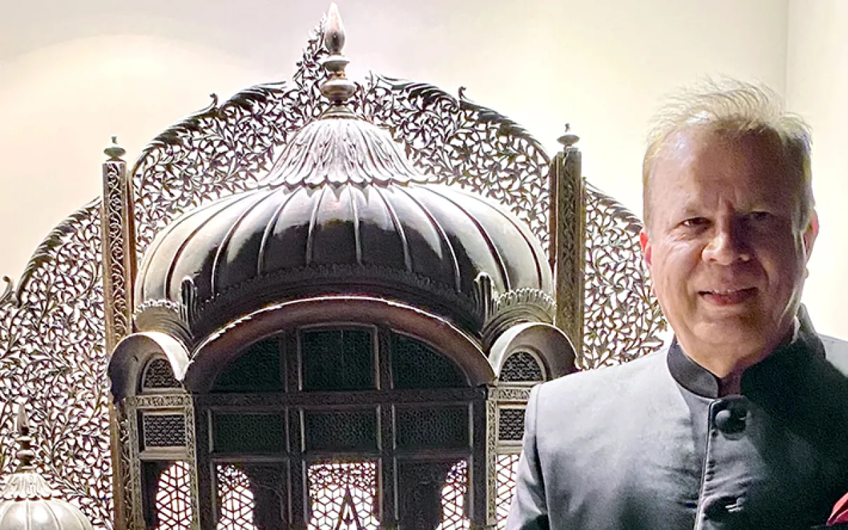 An ornate silver ceremonial object with intricate patterns beside a man in a dark jacket.