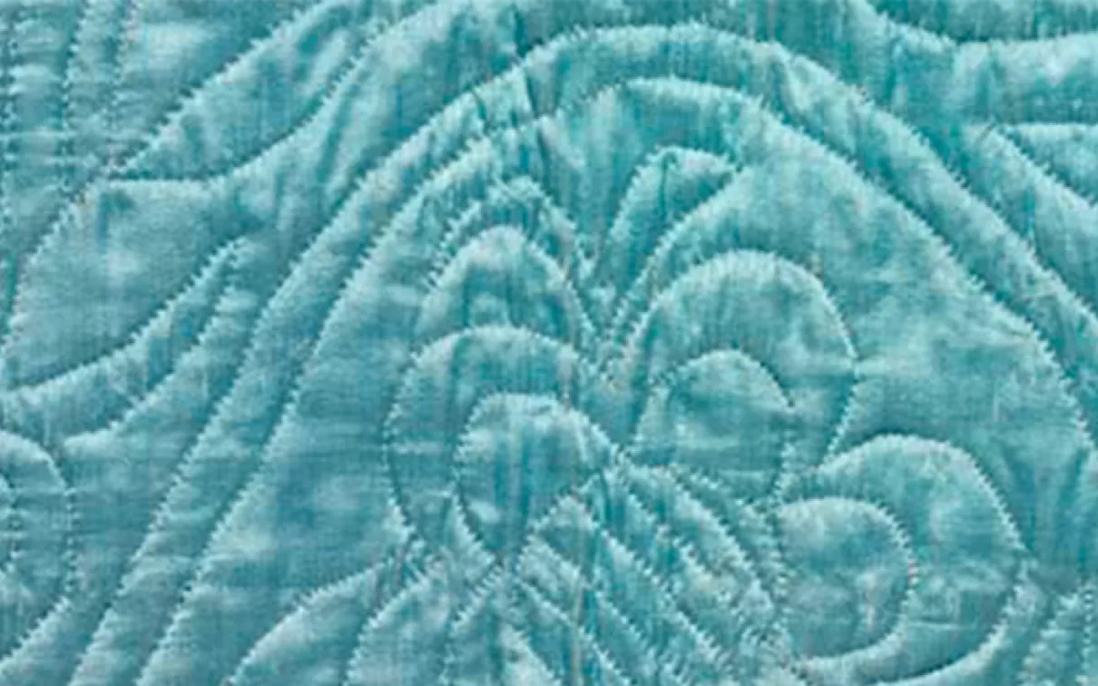 Gros plan d'un tissu bleu clair avec des motifs piqués comprenant un papillon et des lignes symétriques.