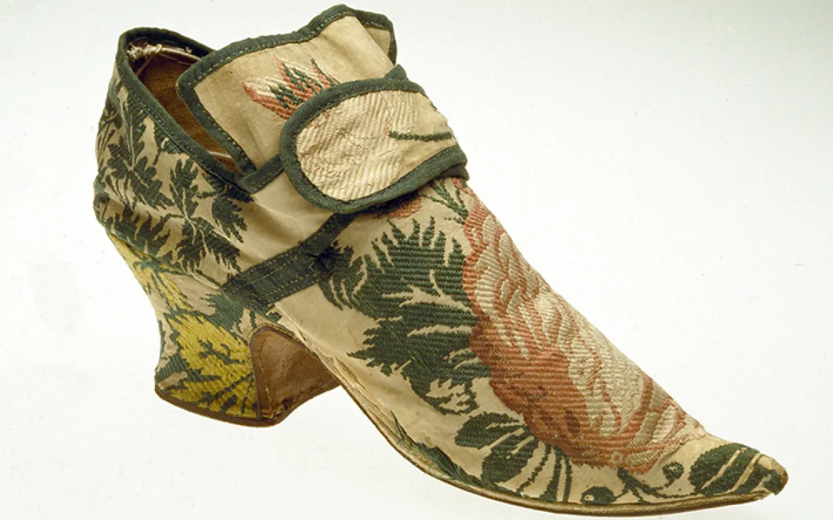 19th-century embroidered silk shoe with floral and leaf patterns in green, pink, and yellow tones.