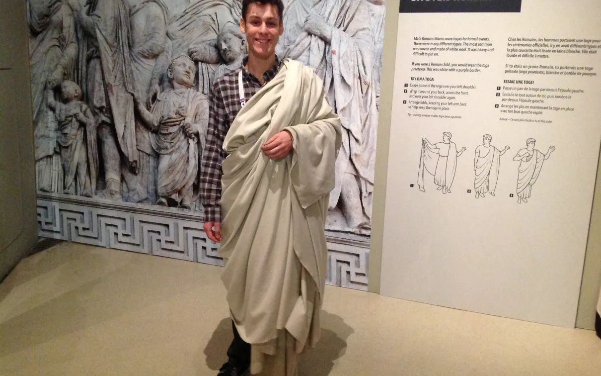A young man wears a white toga
