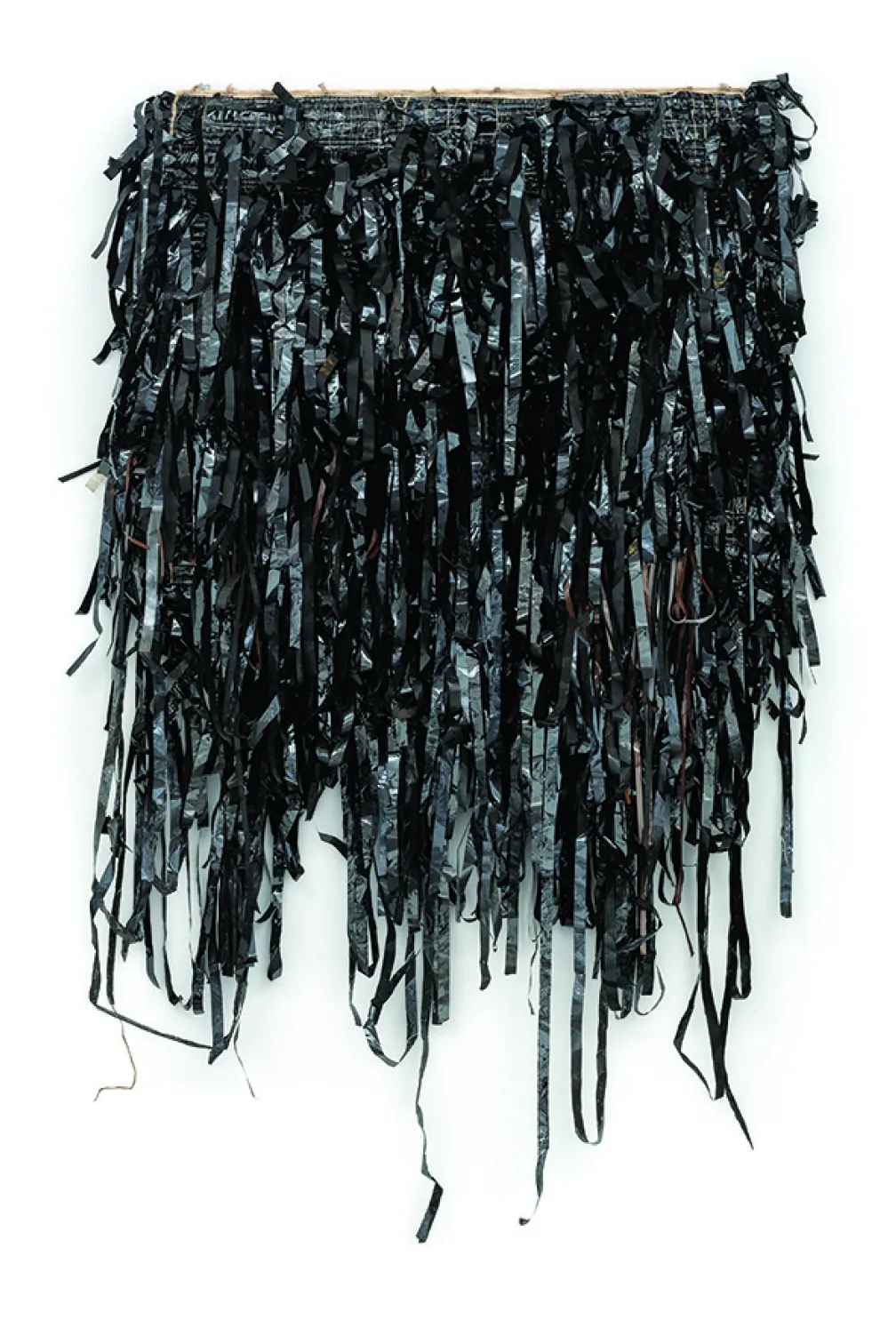 Une œuvre d'art textile composée de bandes noires, brillantes, coupées de manière irrégulière, densément superposées et pendantes.