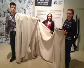 The white fabric is pleated and the young man’s hand is now visible.