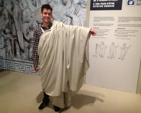 The young man stands with the toga wrapped back over his left shoulder.