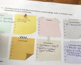 A student writing in a worksheet, brainstorming sustainable solutions in various categories