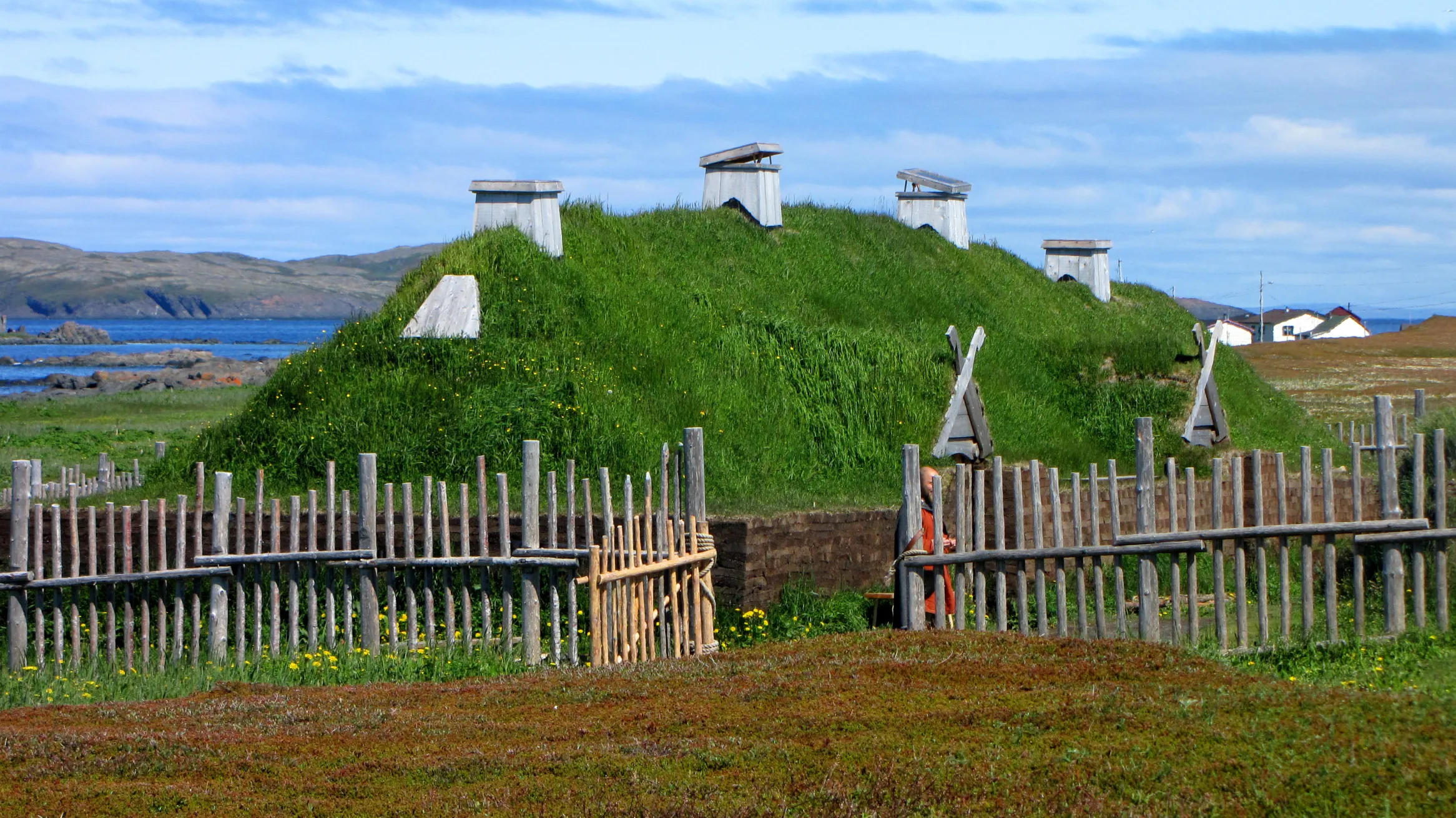 Une habitation dont le toit est recouvert d'herbe et qui est entourée d'une clôture.